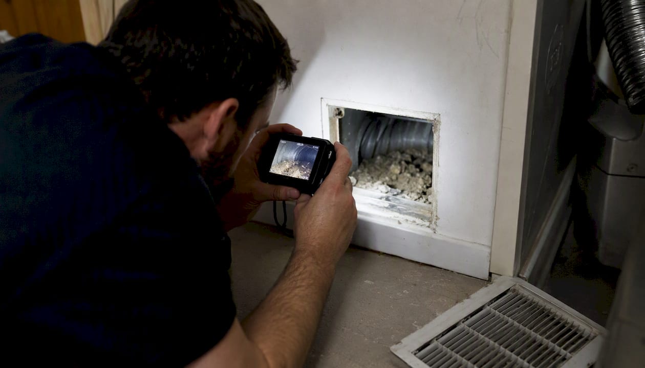 Technician photographing duct interior before cleaning